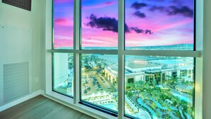Una habitación con ventanas amplias que ofrecen vistas a un paisaje urbano al atardecer.