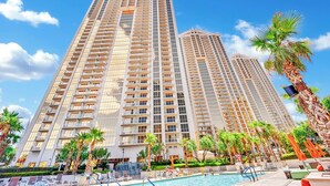 Un hotel moderno de gran altura con varios balcones, una piscina y palmeras.