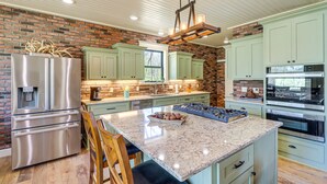 Una cocina con un refrigerador de acero inoxidable, horno empotrado y una isla de granito.