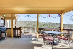A covered outdoor deck with a grill, a table, and chairs. - 8 Mi to Lake Lure! Mtn-View Gem w/ Furnished Deck (Rutherfordton)
