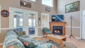 A living room with a sofa, a television, a fireplace, and a door to the outside. - 8 Mi to Lake Lure! Mtn-View Gem w/ Furnished Deck (Rutherfordton)