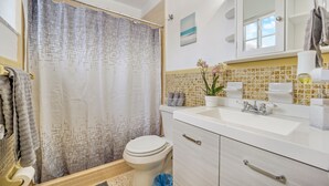 Une salle de bain équipée d’une douche avec rideau, de toilettes, d’un lavabo et de meubles de rangement.