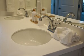 Un baño con dos lavamanos, un espejo y una toalla sobre el mostrador.