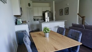 A modern kitchen with white cabinets, a stainless steel refrigerator, and a coffee maker.