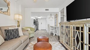 A living room with a sofa, ottomans, a television, and a decorative cabinet. - Beach Access, Pool/Hot Tub, Sleeps 5 - Vet Owned (Gulf Shores)