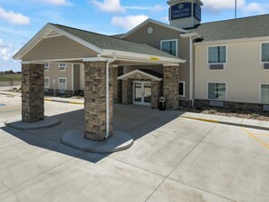 A hotel entrance with a covered walkway, stone pillars, and a clear sky. - Cobblestone Inn & Suites - Boise City (Boise City)