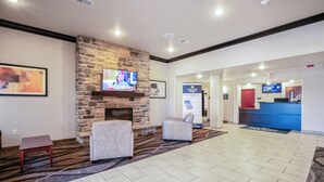 Eine Lobby mit Kamin aus Stein, einem Flachbildfernseher, einem Empfangstresen und einem Teppichboden.