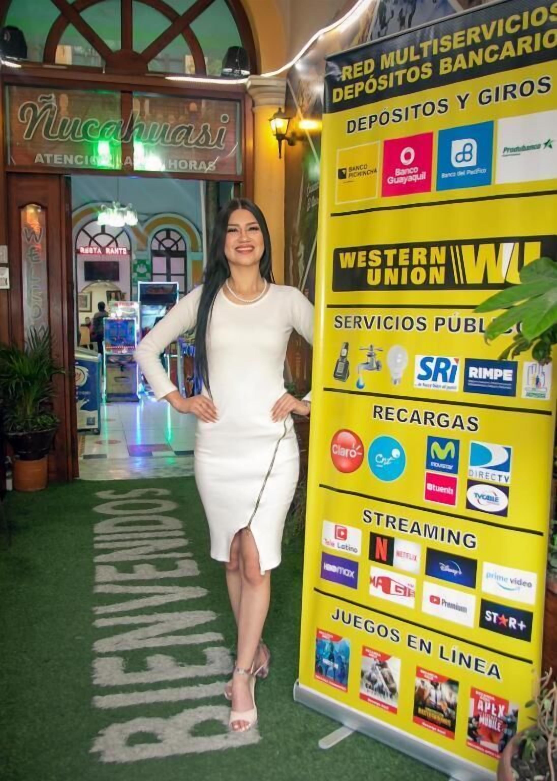 A woman standing in a lobby with a yellow signboard displaying various services and logos.