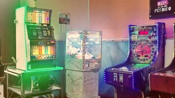 Una habitación con máquinas de videojuegos, un jukebox antiguo y un cartel en la pared.