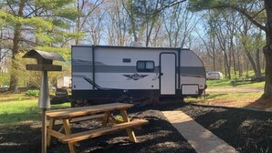 A recreational vehicle (RV) parked in a campground with a picnic table and birdhouse nearby. - Cozy Camper in Villa Ridge (Villa Ridge)