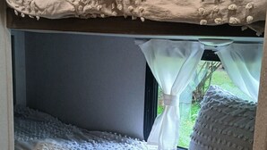 A bunk bed with textured bedding and a window with a view of greenery. - Cozy Camper in Villa Ridge (Villa Ridge)