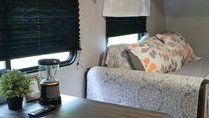 A compact RV interior with a kitchenette, a dining area, and a sleeping berth. - Cozy Camper in Villa Ridge (Villa Ridge)