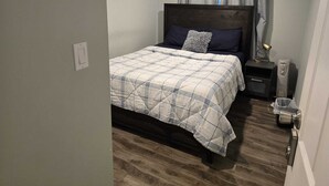 Une chambre à coucher bien rangée, avec un lit, des tables de chevet et une lampe.