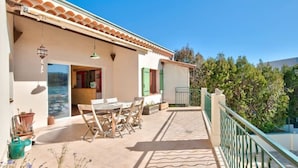 Une terrasse avec une table et des chaises, une balustrade et une vue sur la mer.