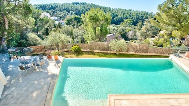 Une piscine avec vue sur une colline boisée.