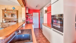 Une cuisine compacte dotée d’un plan de travail en bois, d’un four encastré et d’un réfrigérateur blanc.
