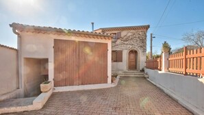 Une maison avec une allée pavée, une grande porte de garage en bois et un mur en pierre.