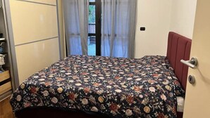 A room with a bed, a wardrobe, and a door leading to a balcony.