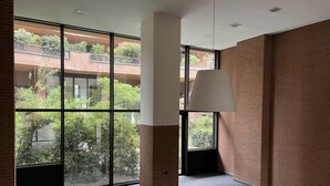 A spacious room with large windows, a modern ceiling light, and a brick wall.
