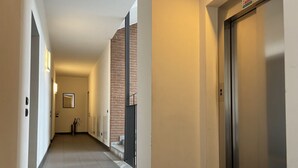 A corridor with a brick wall, a door, and a sign on the wall.