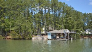 A houseboat on a lake surrounded by dense forest. - Lake Life Escape - The Point on Lake Gaston (Henrico)