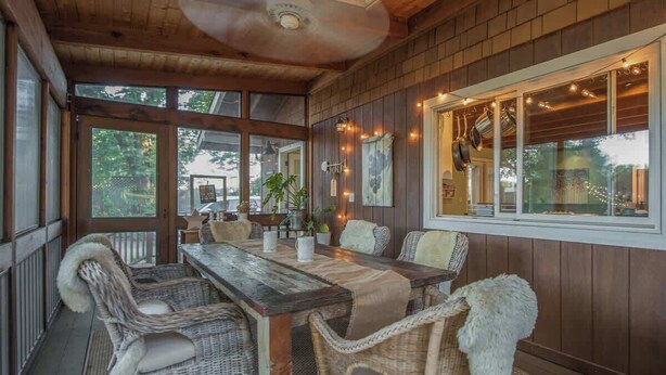 Un espace de restauration intérieur aménagé avec des meubles en osier, une table en bois et des guirlandes lumineuses.