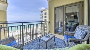 A balcony with a view of the beach, wicker furniture, and a glass door leading to an interior space. - Costal Condo - Ocean & Pool Views - Sleeps 6 (Panama City Beach)