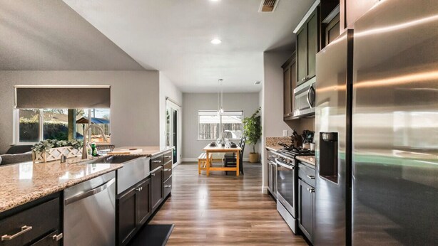 A modern kitchen with stainless steel appliances, a wooden dining table, and a view of the backyard. - Cal King Hi-tech Vaca Pool Home | Ideal 4 Families (Chico)