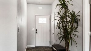 A hallway with a white door, a bench, and a potted plant. - Cal King Hi-tech Vaca Pool Home | Ideal 4 Families (Chico)