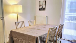 Een eetkamer met een tafel voor zes personen, een radiator, een lamp en een afbeelding van de Eiffeltoren aan de muur.