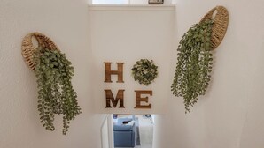 A hallway with a sign reading "HOME" flanked by woven baskets with hanging greenery.