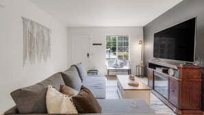 A modern living room with a grey sofa, a flat-screen TV, and a wooden entertainment unit.
