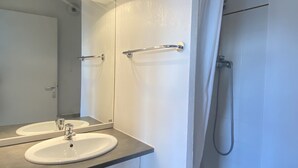 Un baño con dos lavamanos, una ducha y un espejo.