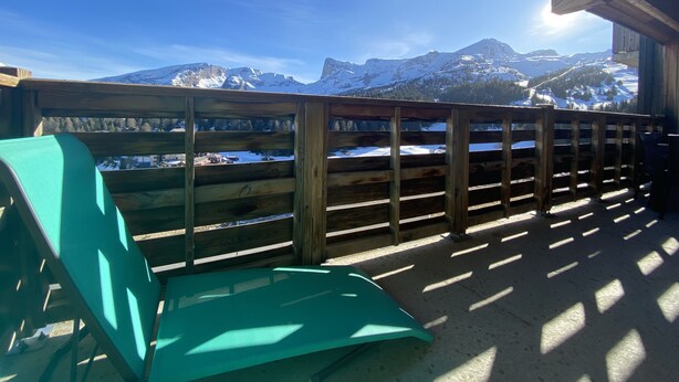 Un balcón de madera con vista a montañas nevadas.