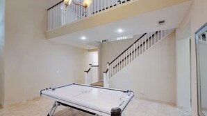 A spacious indoor area with a pool table, a staircase, and a balcony. - King Beds Castle | Air Hockey | Room TVs | Firepit (Chico)