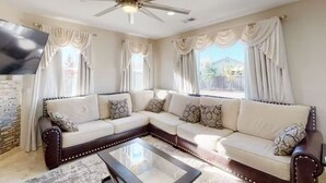 A living room with a sectional sofa, a glass coffee table, and a ceiling fan. - King Beds Castle | Air Hockey | Room TVs | Firepit (Chico)