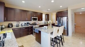 A modern kitchen with dark wood cabinets, stainless steel appliances, and a granite countertop. - King Beds Castle | Air Hockey | Room TVs | Firepit (Chico)