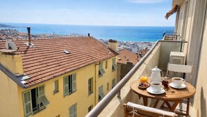 A balcony with a table set for breakfast, overlooking a coastal cityscape. - Beautiful view Walking distance from the center (Nice)