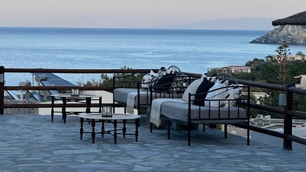 Una terraza con suelo de piedra, mobiliario exterior y vistas al mar.