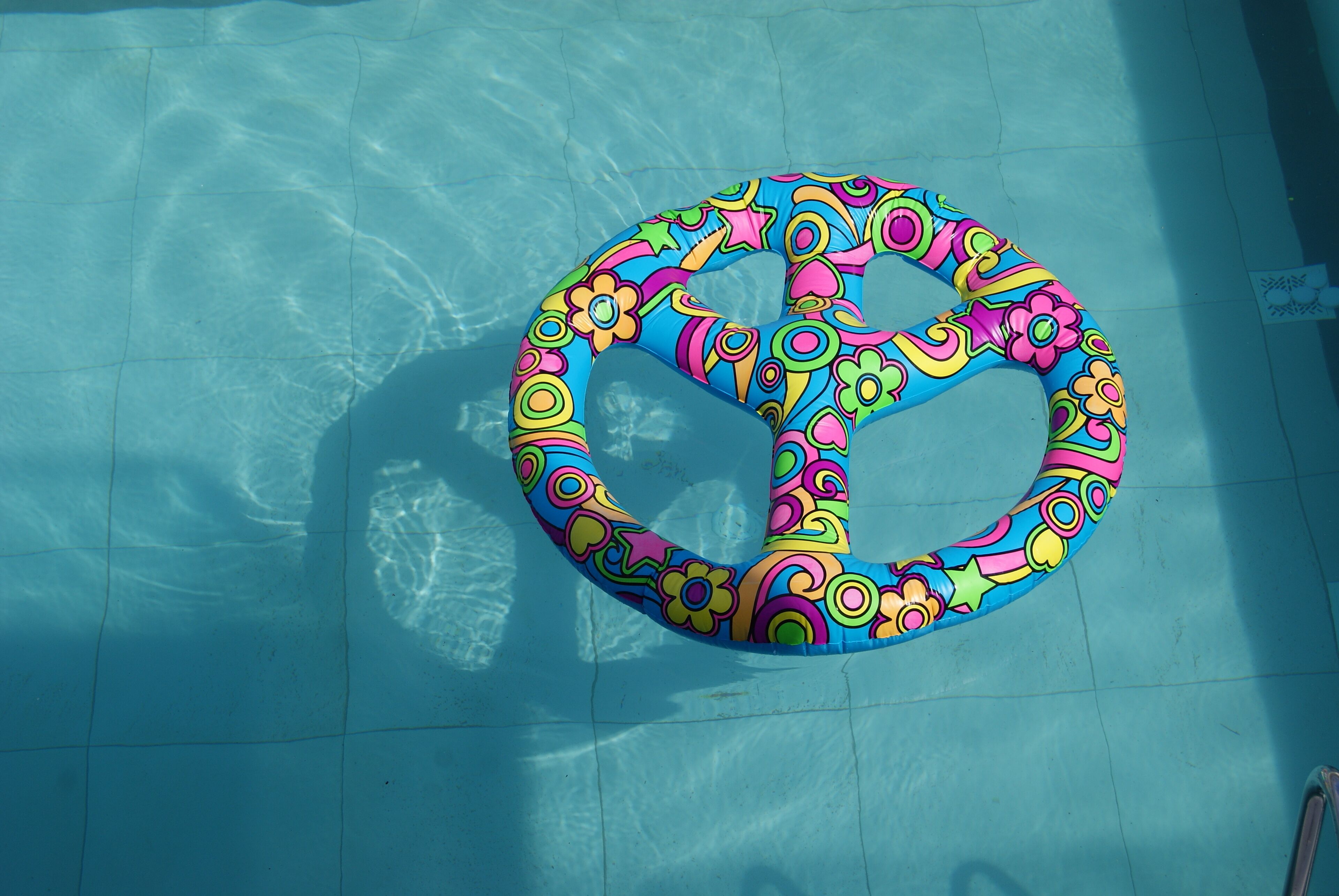 A colorful, flower-patterned pool float in a swimming pool.
