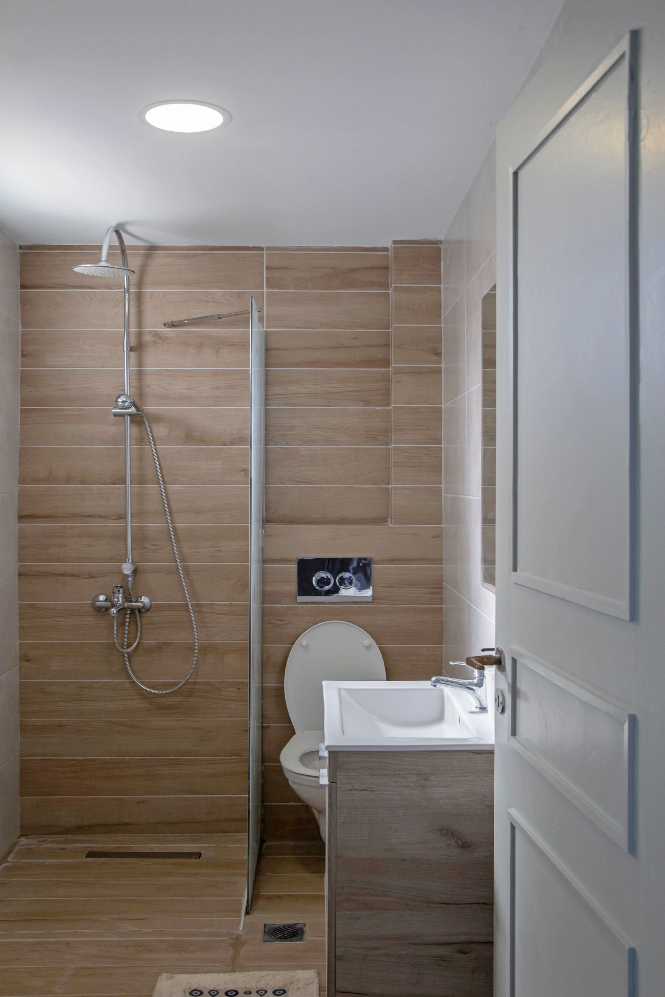 Une salle de bain moderne avec un lambris en bois, une douche, des toilettes et un lavabo.