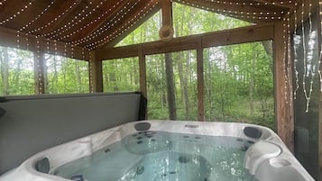 Un jacuzzi con panel de control, rodeado de vigas de madera y luces colgantes.