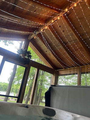 Un intérieur rustique en bois, agrémenté de guirlandes lumineuses, de grandes fenêtres et offrant une vue sur les arbres.