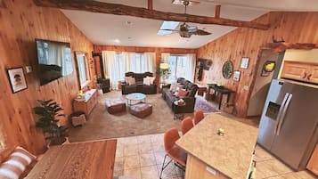 Interior acogedor estilo cabaña, con detalles de madera, un comedor, una cocina y una sala de estar con chimenea.