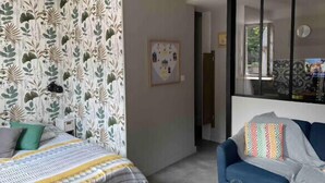 Ein Zimmer mit einem Bett, einer Couch, einem Fenster und einer Wand mit Blätermuster.