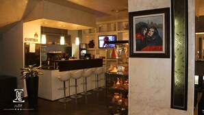 A hotel bar area with a café, bar stools, a television, and a framed painting. - ABC Hotel - Alger Centre (Algiers)