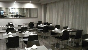 A hotel dining area with multiple tables and chairs, a large mirror, and a view of the kitchen area. - ABC Hotel - Alger Centre (Algiers)