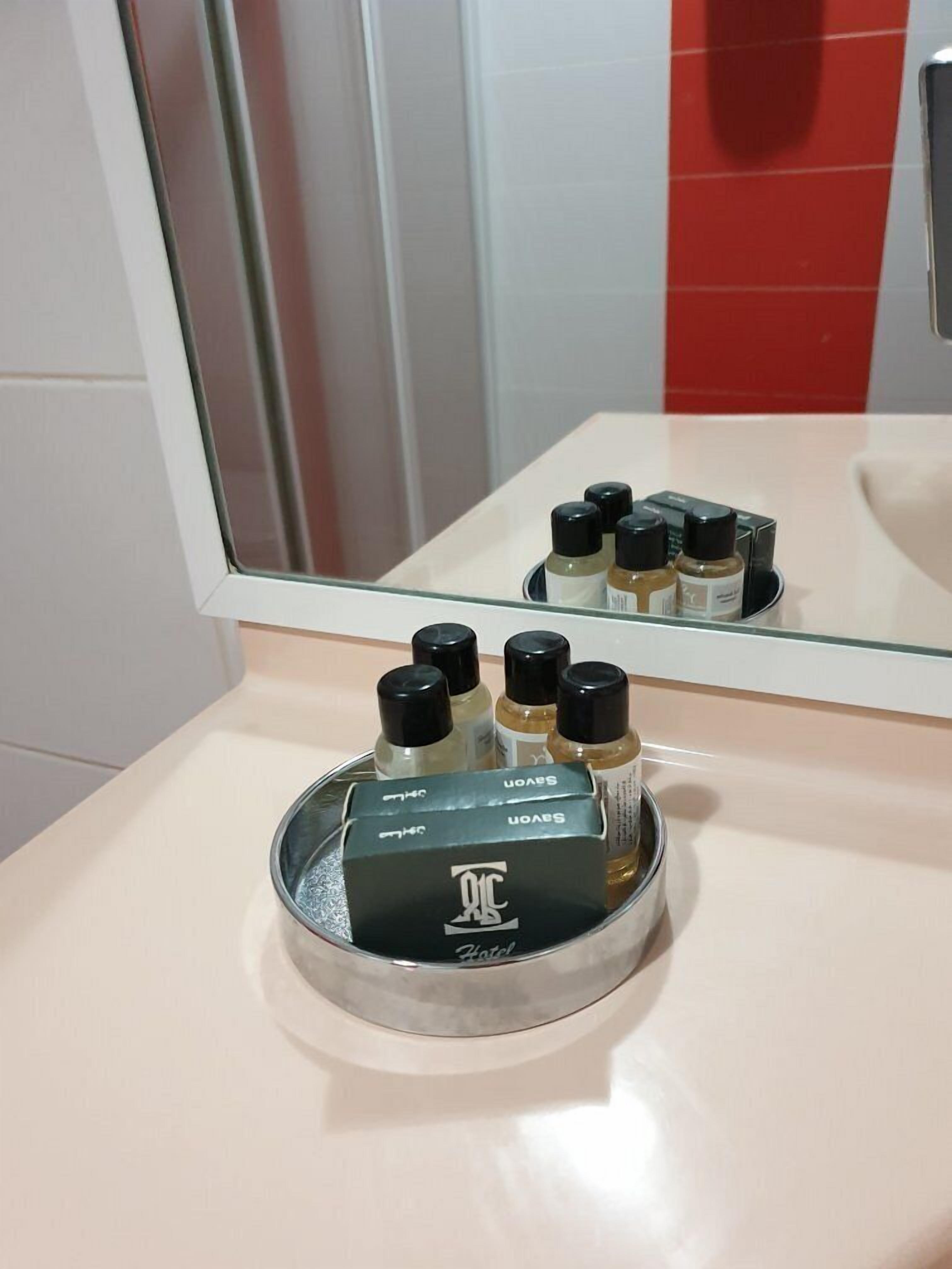 Une salle de bain avec un miroir, un lavabo et un plateau contenant plusieurs flacons de produits de toilette.
