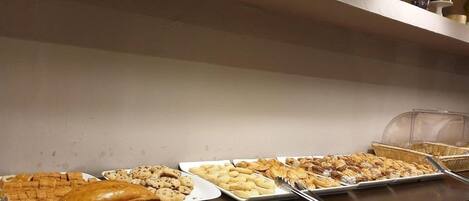 A buffet with various baked goods and pastries.