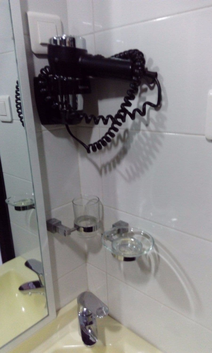 A bathroom with a mirror, sink, and a towel rack with a coiled towel.